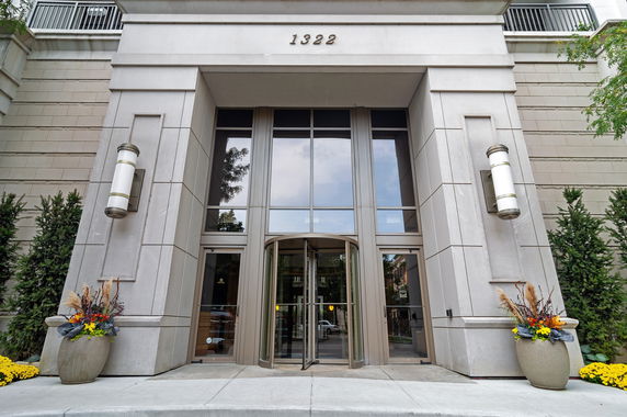 Front view of a building entrance with large glass doors and towering pillars.