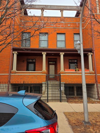 Front view of a two-story brick building with columns and a small entrance staircase.