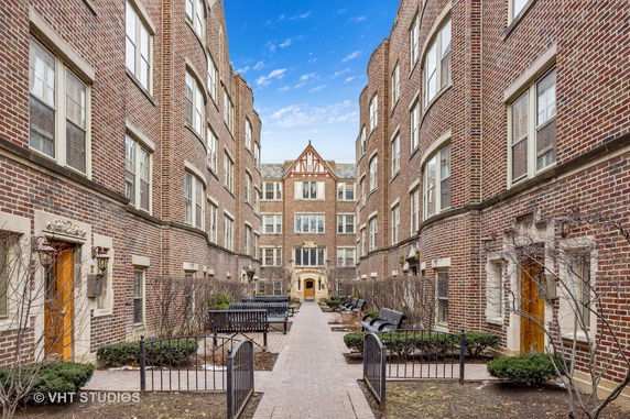Front view of a brick apartment complex with a central courtyard.