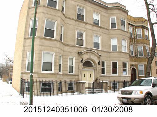 Front view of a multi-story building with bay windows and a gated entrance.