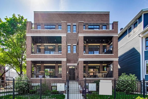 Front view of a multi-story brick apartment building with balconies.