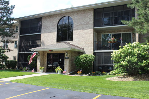 Front view of a three-story brick apartment building with balconies and a central glass window.