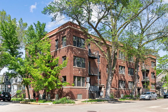 Front view of a multi-story brick apartment building with balconies.