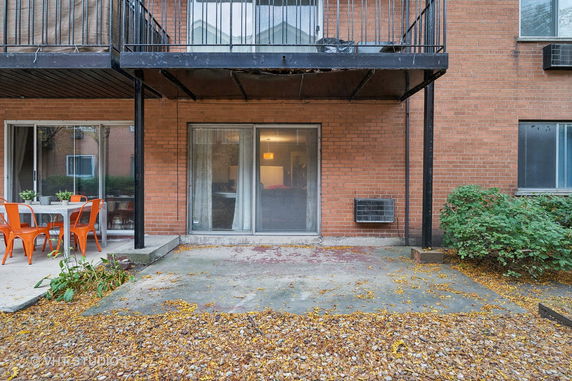 Front view of a brick apartment building with a patio and balcony.