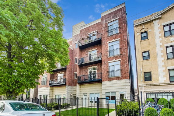 Front view of a multi-story brick apartment building with balconies.