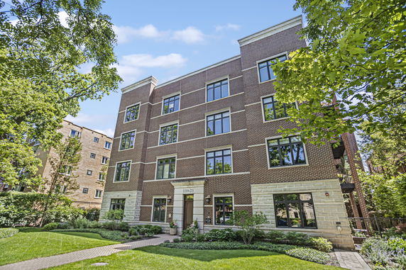 Front view of a multi-story brick apartment building with large windows.