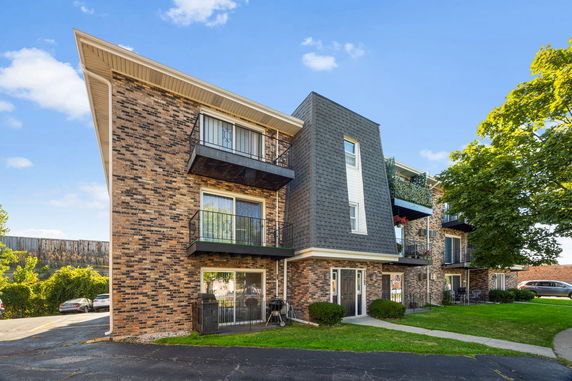 Front view of a multi-story brick apartment building with balconies.