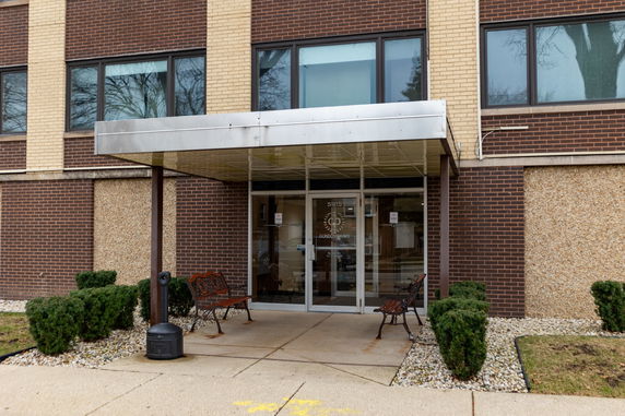 Front view of a building entrance with glass doors and brick exterior.