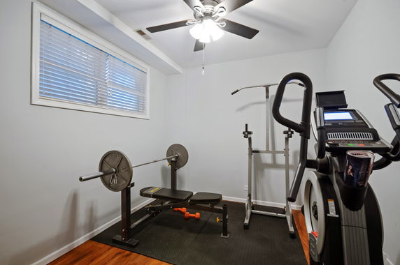 Indoor room with gym equipment including a bench press and elliptical machine.