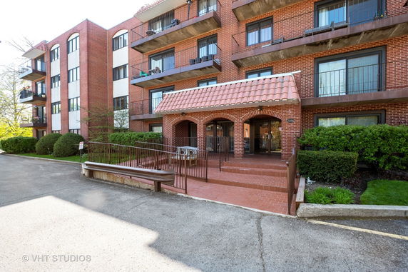 Front view of a multi-story brick apartment building with balconies.