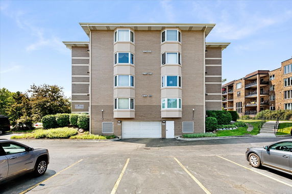 Front view of a multi-story brick apartment building with garage doors at the base.