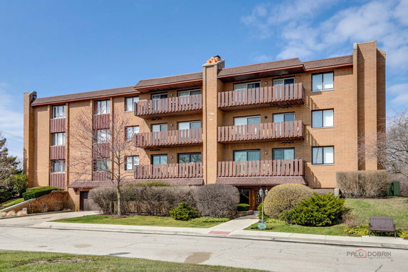 Front view of a four-story brick apartment building with balconies.