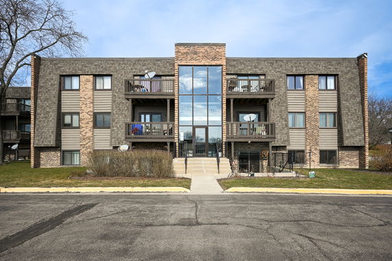 Front view of a multi-story apartment building with balconies and large windows.