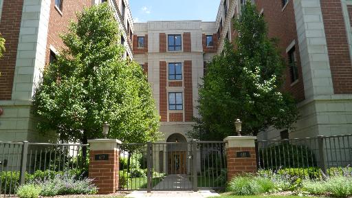 Front view of a multi-story brick building with a gated entrance.