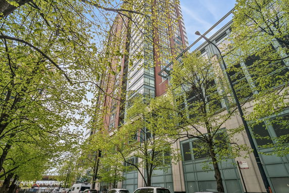 View of a tall brick and glass building with trees in the foreground.