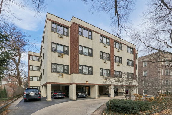 Front view of a multi-story building with covered parking on the ground level.