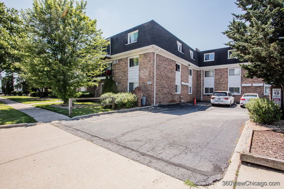 Front view of a three-story brick apartment building with a gabled roof.