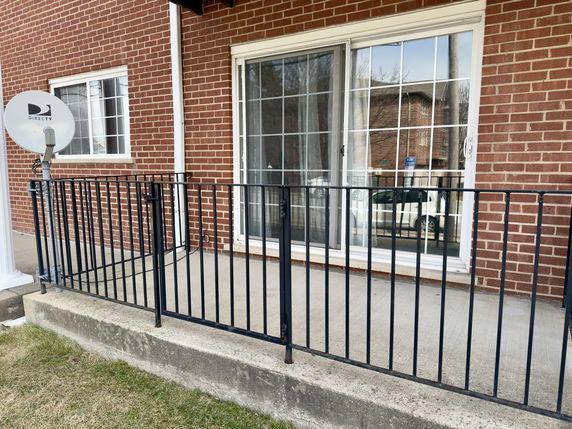 Front view of a brick building with a metal railing and a satellite dish.