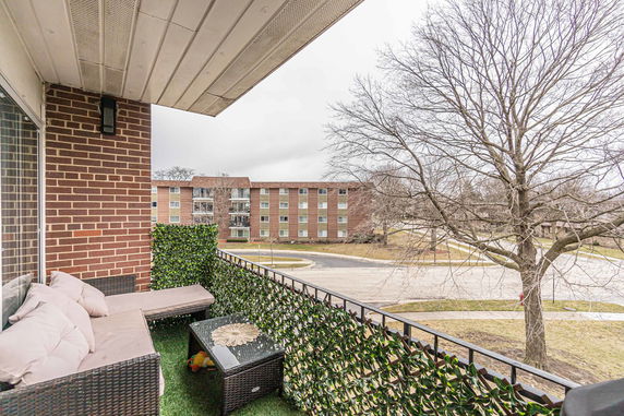 View from a balcony overlooking a residential area with a tree and a building.