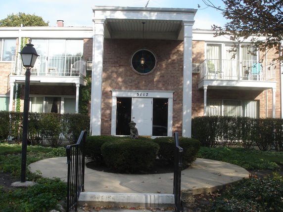 Front view of a two-story brick building with balconies and white trim.