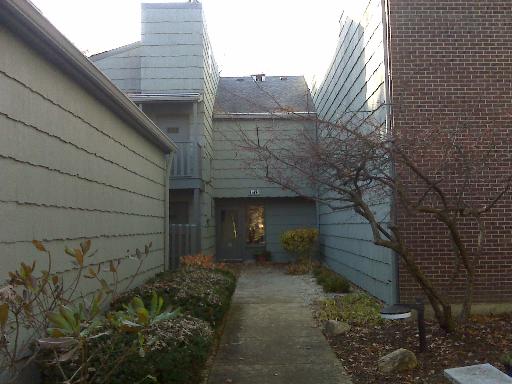 Front view of a narrow, two-story residential building with gray siding and a central entrance.