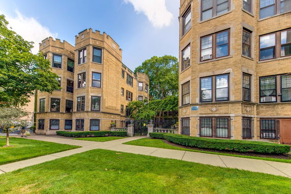 Front view of a multi-story brick apartment building with large windows.