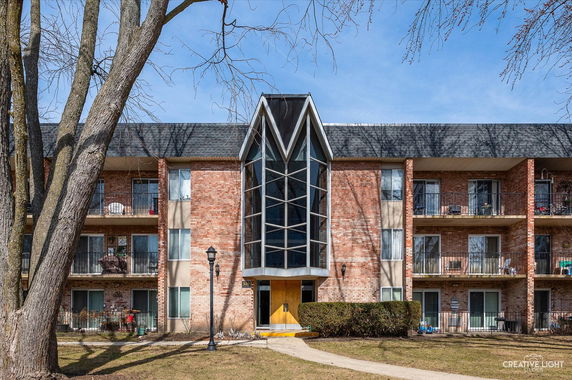 Front view of a three-story brick apartment building with glass entrance.