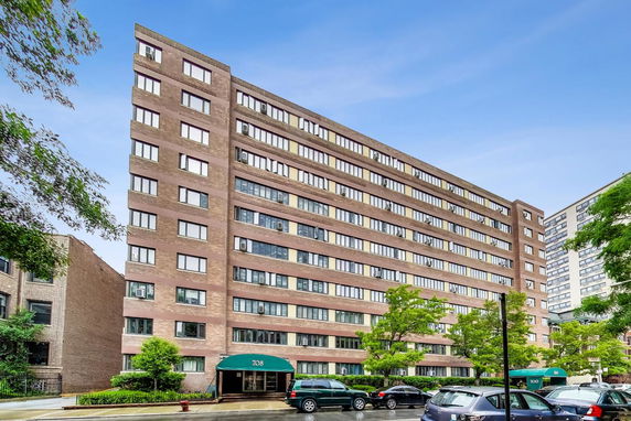 Front view of a mid-rise apartment building with multiple windows and entrance awnings.