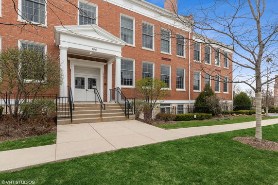 Front view of a multi-story brick building with white columns and steps leading to the entrance.