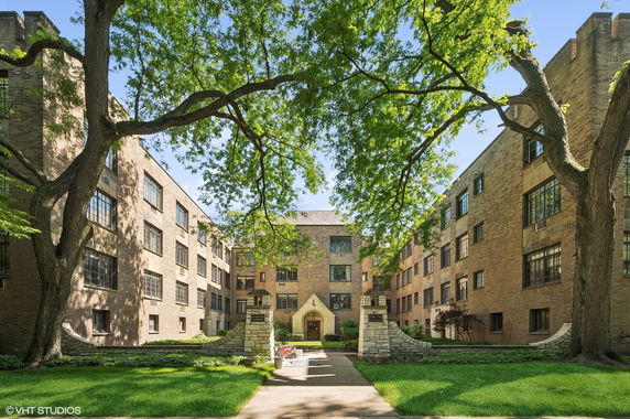 Front view of a multi-story apartment building with a central courtyard.