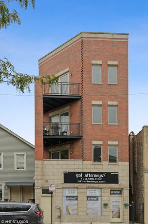 Front view of a multi-story brick building with balconies.