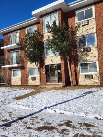 Front view of a multi-story brick apartment building with balconies.