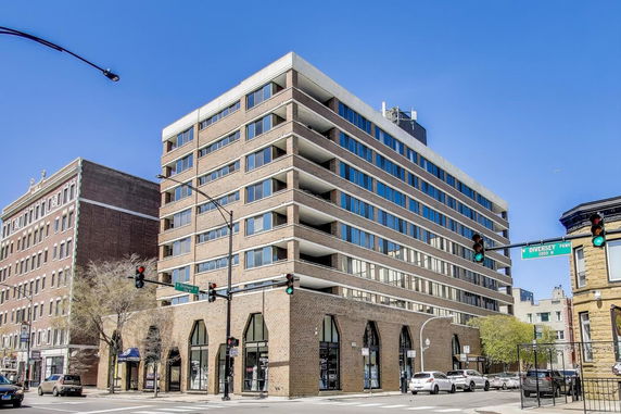 Front view of a multi-story building with large windows and a brick facade.