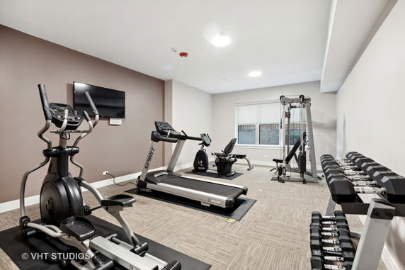 Indoor gym area with exercise equipment, including treadmills, an elliptical machine, and weights.