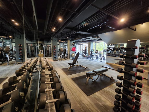 Indoor gym area with various exercise equipment and mirrors.