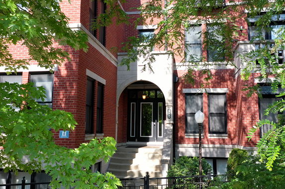 Front view of a brick apartment building with arched entrance and steps.