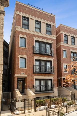 Front view of a multi-story brick building with balconies and a gated entrance.