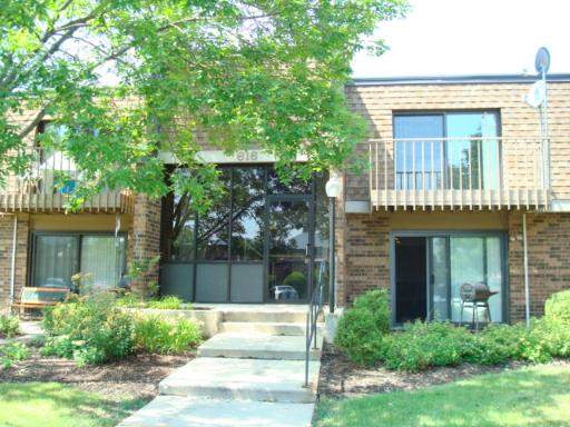 Front view of a two-story brick apartment building with balconies and a central entrance.