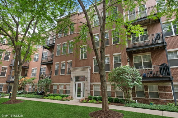 Front view of a multi-story brick apartment building with balconies.