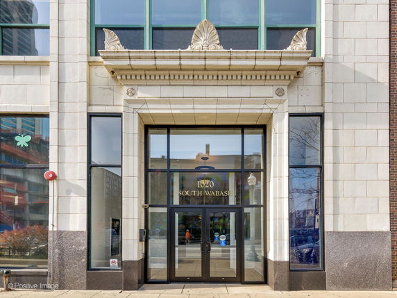 Front view of a multi-story building with large windows and decorative stone work.