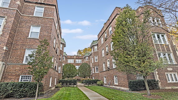 Front view of a brick apartment building with multiple stories and windows.