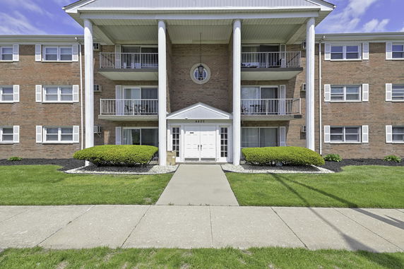 Front view of a multi-story building with balconies and columns.