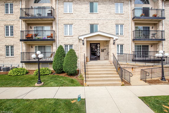 Front view of a multi-story brick apartment building with balconies.