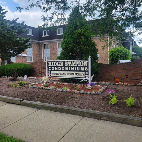 Front view of a condominium building with a sign for Ridge Station Condominiums in front.
