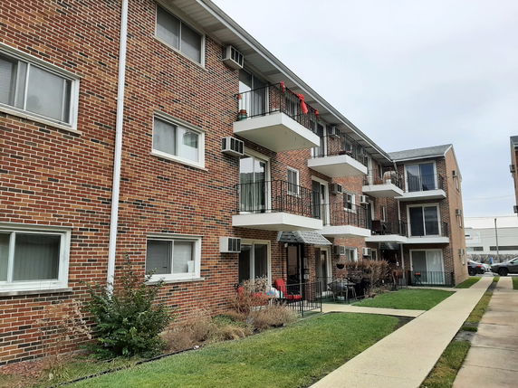 Front view of a multi-story brick apartment building with balconies.