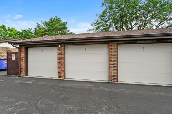 Row of three garage doors in a brick building.