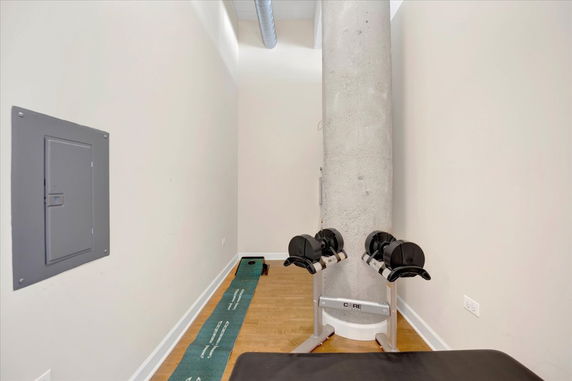Indoor area with a concrete pillar, dumbbell set, and exercise mat.