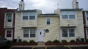 Front view of a two-story townhouse with beige siding and white trim.