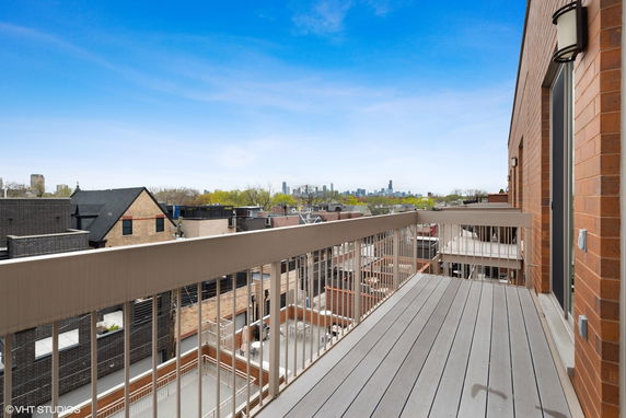 View from a balcony overlooking city rooftops with a distant skyline.