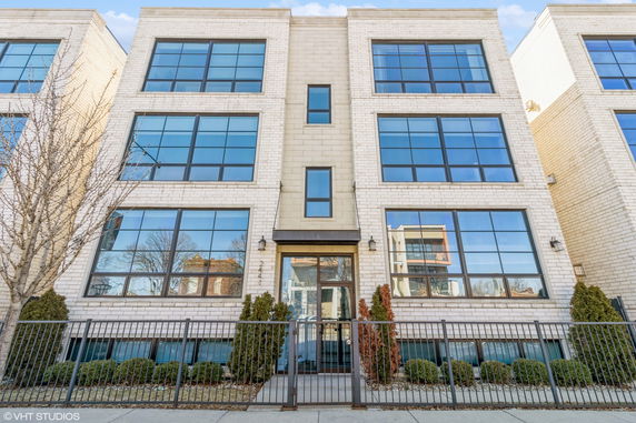 Front view of a modern multi-story building with large windows and a gated entrance.